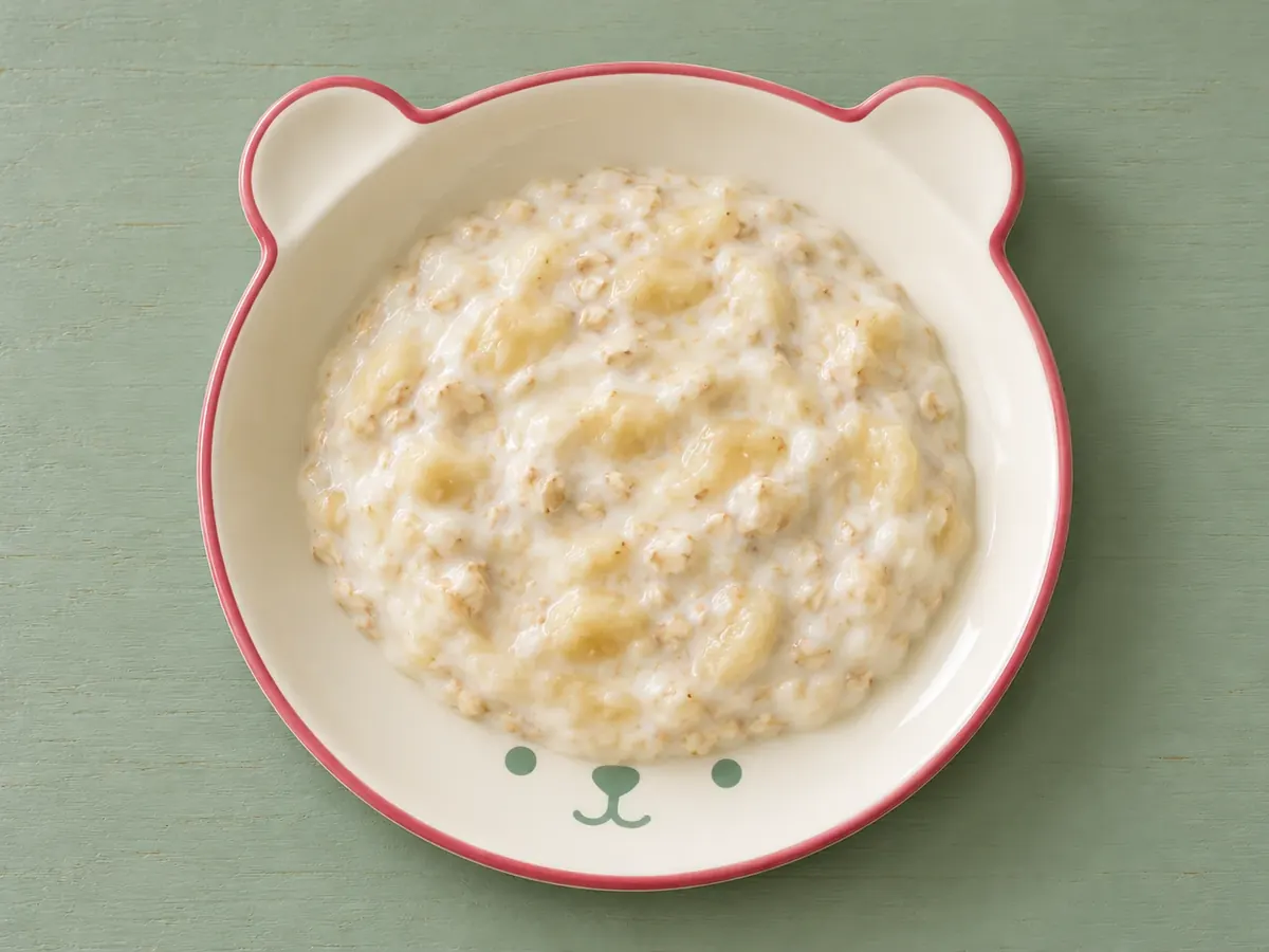 Naturjoghurt mit Banane auf cremefarbenem Keramikgeschirr mit himbeerfarbenem Rand auf salbeifarbenem Holz.